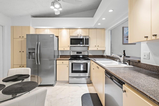 kitchen with ceiling fan, sink, stainless steel appliances, vaulted ceiling, and a textured ceiling