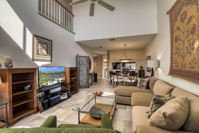 living room with ceiling fan and a towering ceiling