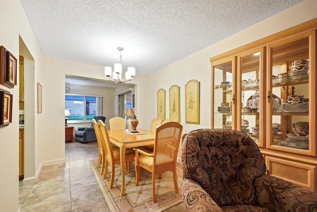 dining room with a notable chandelier, baseboards, and a textured ceiling