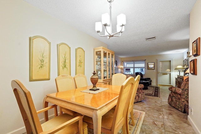 dining area featuring a notable chandelier, baseboards, visible vents, and a textured ceiling