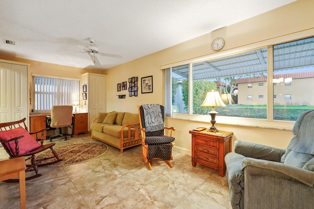 living room with baseboards, visible vents, and ceiling fan