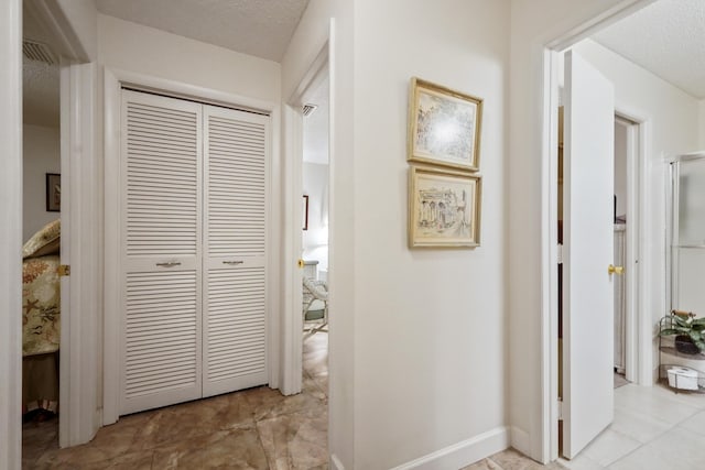 hall featuring baseboards and a textured ceiling