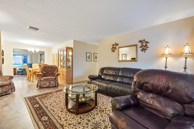 living room featuring a textured ceiling, light tile patterned floors, visible vents, and a chandelier