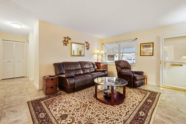 living area with light tile patterned floors, baseboards, and a textured ceiling