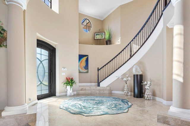 foyer entrance with ornate columns, crown molding, and a high ceiling