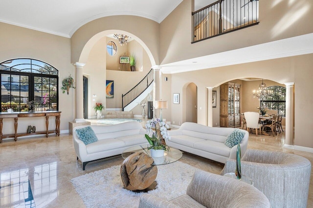 living room with decorative columns, ornamental molding, a high ceiling, and a chandelier