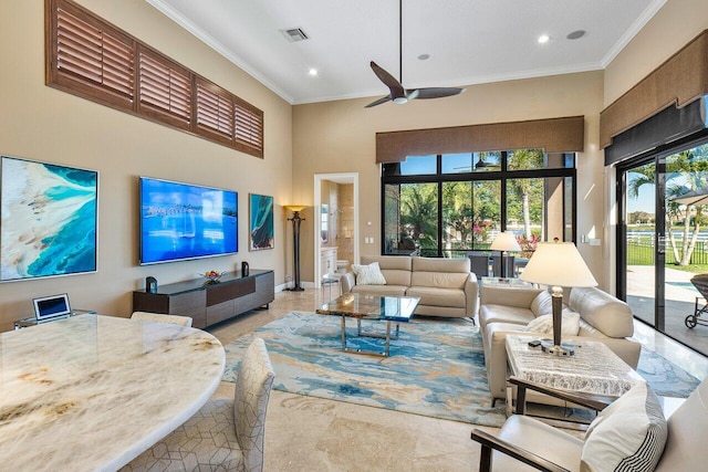 living room featuring ceiling fan, ornamental molding, and a towering ceiling