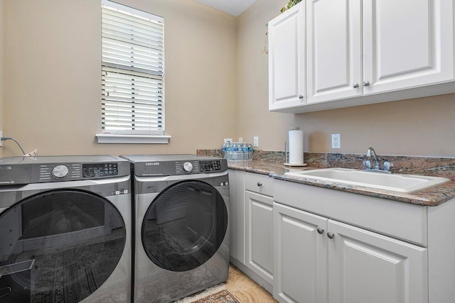 washroom with cabinets, washing machine and dryer, and sink