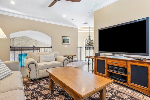 living room with ceiling fan, vaulted ceiling, and ornamental molding