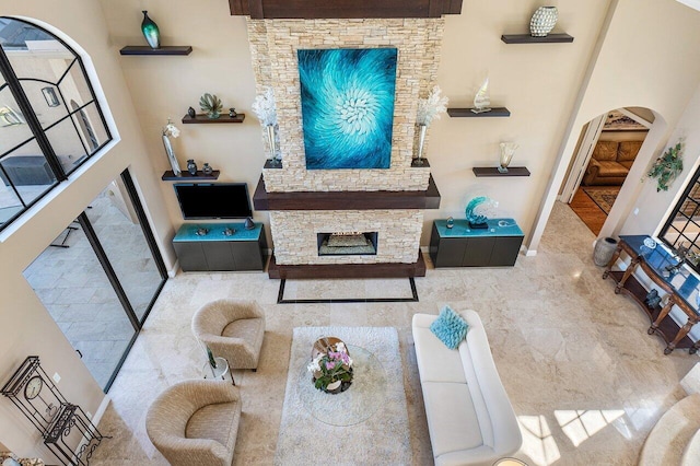 living room with a fireplace and a towering ceiling