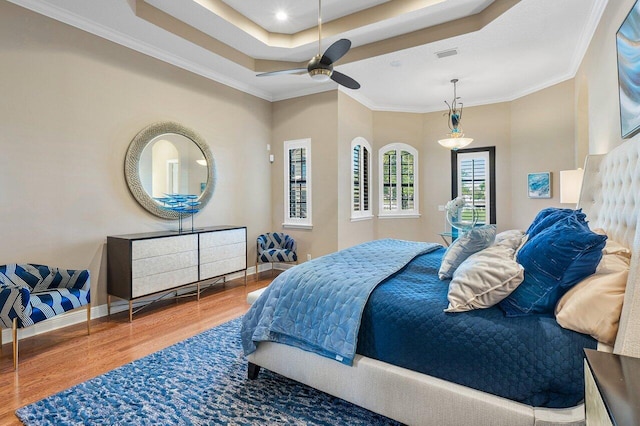 bedroom with a tray ceiling, crown molding, ceiling fan, and hardwood / wood-style flooring