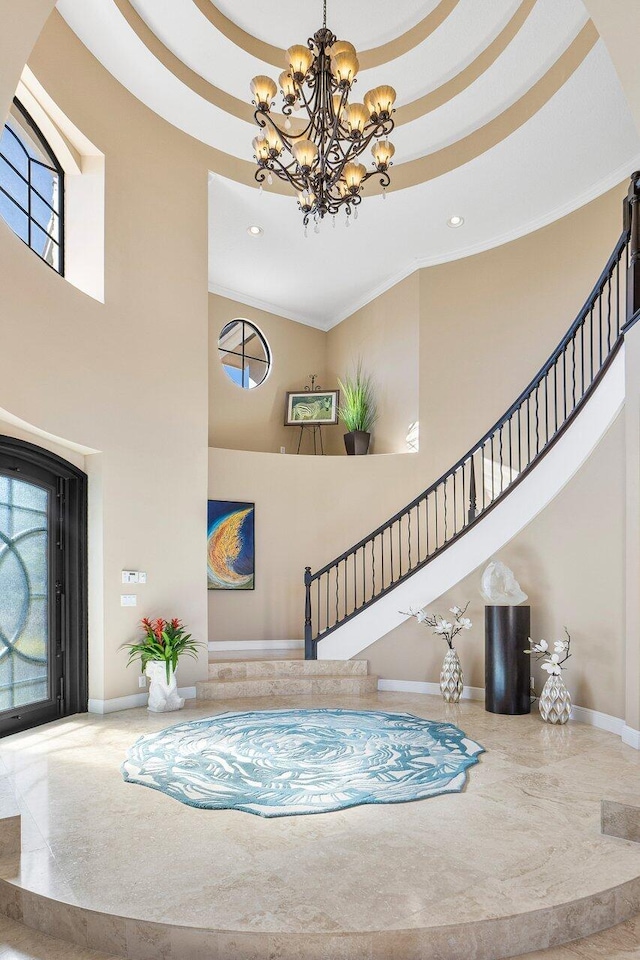 foyer entrance featuring crown molding, a chandelier, and a high ceiling