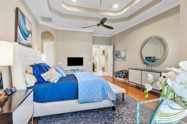 bedroom featuring hardwood / wood-style flooring, ceiling fan, a raised ceiling, and ornamental molding