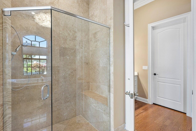 bathroom with hardwood / wood-style flooring, a shower with door, and crown molding