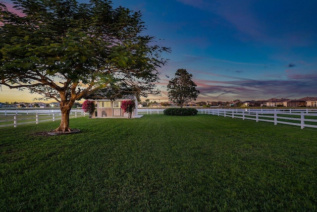 yard at dusk featuring a rural view