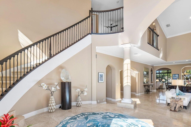 entryway with ornate columns, a high ceiling, and ornamental molding