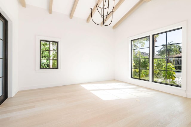 spare room featuring a chandelier, light wood-type flooring, a healthy amount of sunlight, and beam ceiling