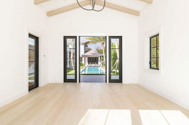 interior space featuring beam ceiling, light wood-type flooring, and french doors