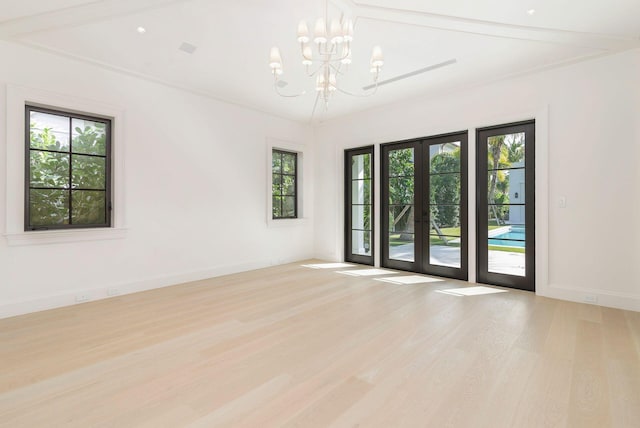 unfurnished room with a notable chandelier, french doors, and light wood-type flooring