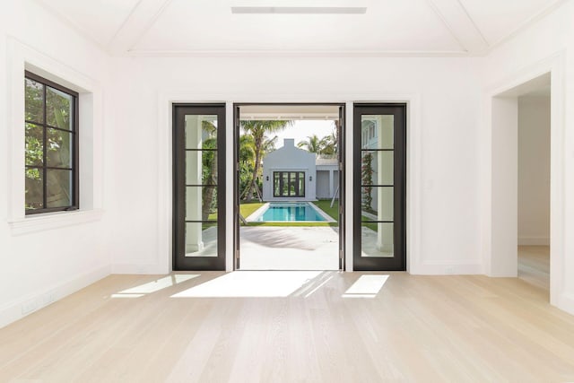 doorway to outside featuring beamed ceiling, light hardwood / wood-style flooring, coffered ceiling, and plenty of natural light