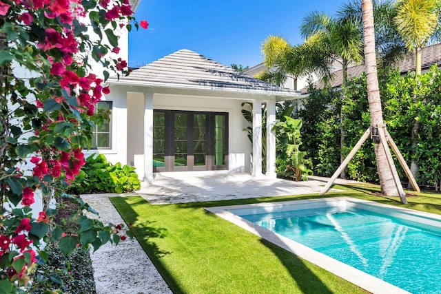 view of swimming pool with a patio, a lawn, and an outbuilding