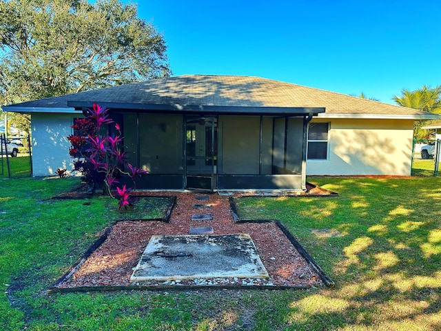 back of property with a yard and a sunroom