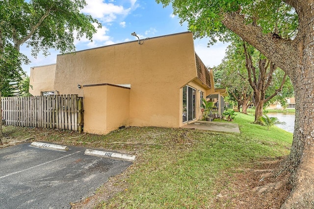 view of side of home with a patio area, a water view, and a yard