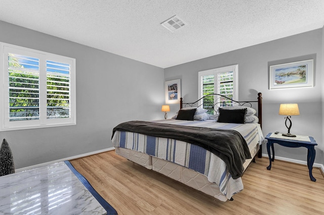 bedroom with a textured ceiling and light wood-type flooring