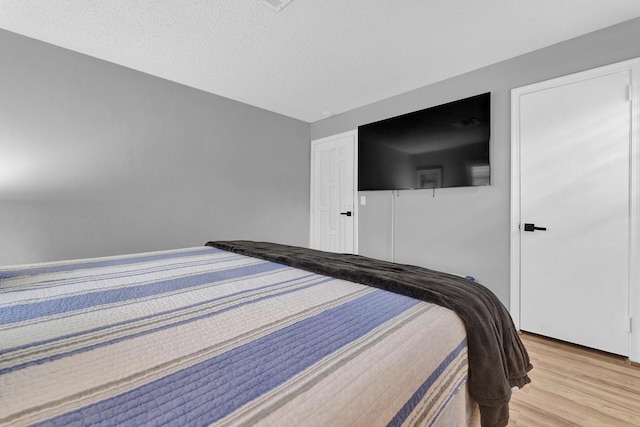 bedroom with light hardwood / wood-style flooring and a textured ceiling