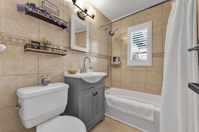 full bathroom with vanity, toilet, shower / bathtub combination with curtain, a textured ceiling, and tile walls