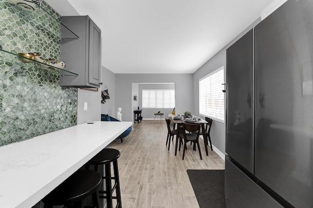 kitchen with gray cabinets, a kitchen bar, light hardwood / wood-style floors, and fridge