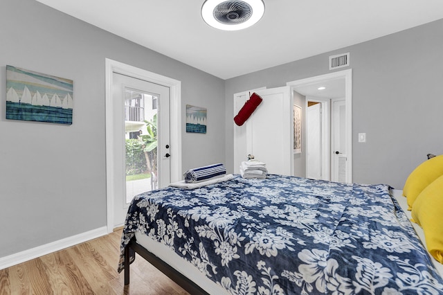 bedroom featuring access to exterior, wood-type flooring, and multiple windows