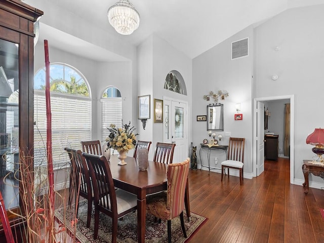 dining space featuring dark hardwood / wood-style flooring, high vaulted ceiling, and a chandelier