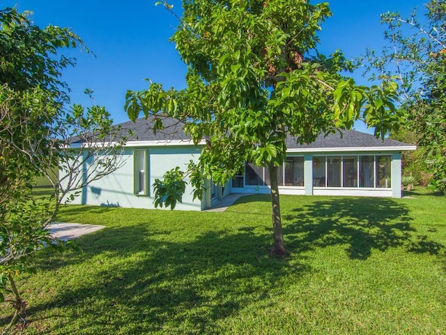 back of property featuring a yard and a sunroom