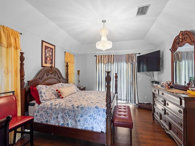 bedroom featuring a raised ceiling, dark hardwood / wood-style flooring, and a notable chandelier