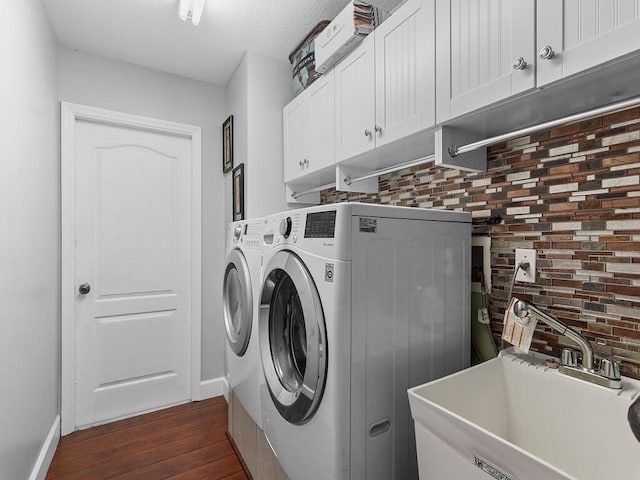 clothes washing area with cabinets, washer and clothes dryer, dark wood-type flooring, and sink