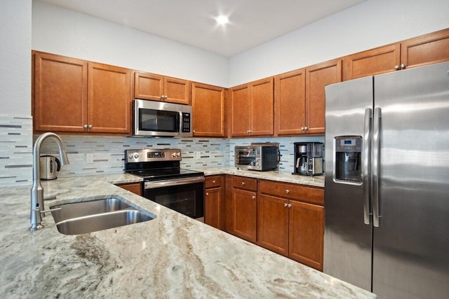 kitchen featuring tasteful backsplash, light stone countertops, sink, and stainless steel appliances