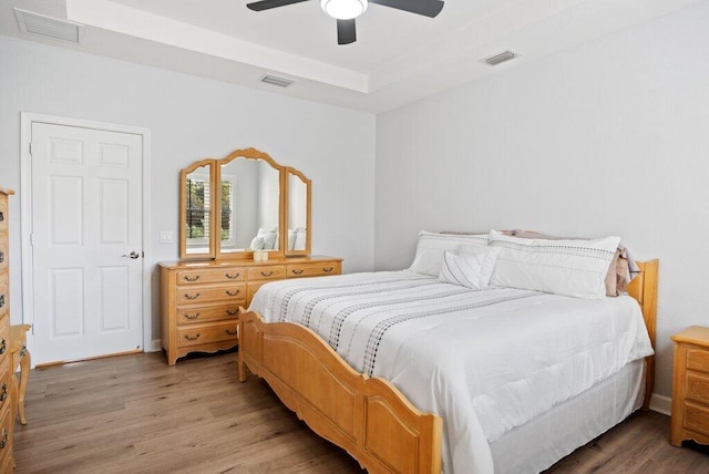 bedroom with a raised ceiling, ceiling fan, and hardwood / wood-style floors