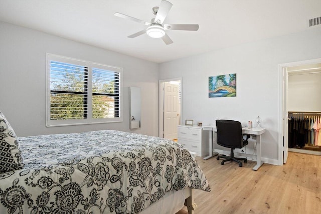 bedroom featuring ceiling fan, light hardwood / wood-style floors, a walk in closet, and a closet