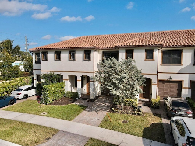 mediterranean / spanish home with a garage and a front lawn