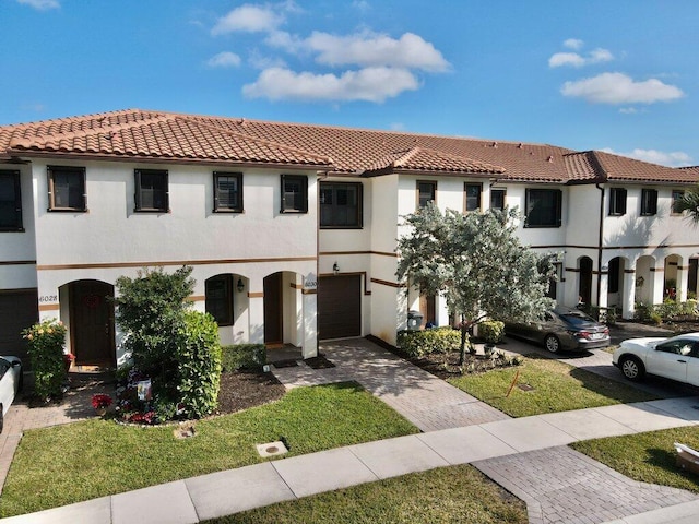 mediterranean / spanish-style house featuring a garage and a front lawn