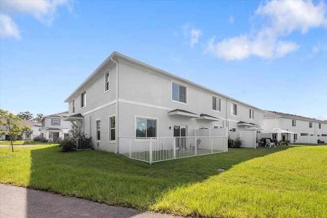 rear view of house featuring a yard and central AC