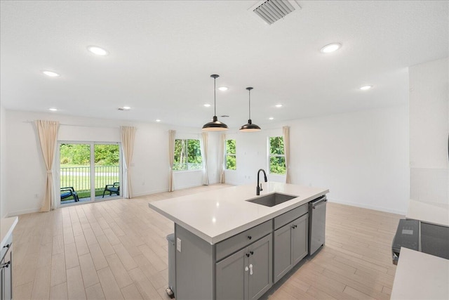 kitchen with sink, a center island with sink, dishwasher, gray cabinets, and hanging light fixtures