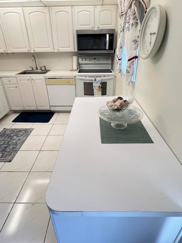 kitchen with white cabinets, light tile patterned floors, white appliances, and sink