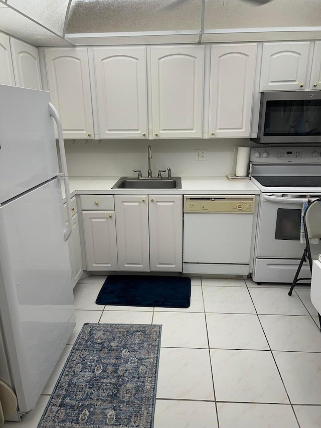 kitchen with white cabinets, light tile patterned flooring, white appliances, and sink