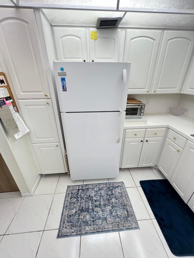 kitchen featuring white fridge, white cabinetry, and light tile patterned floors