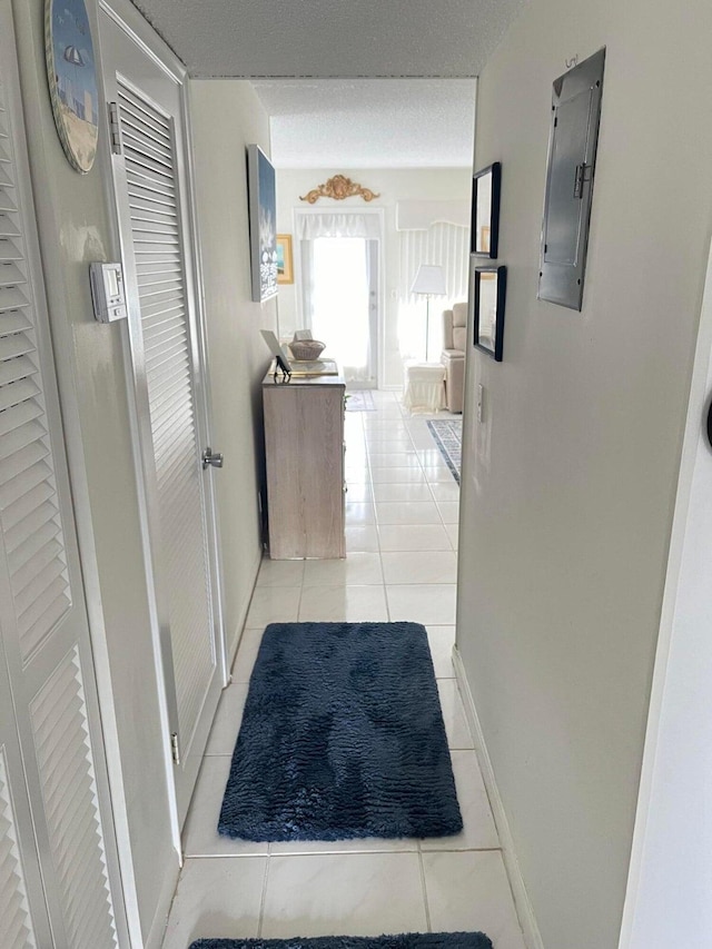 corridor featuring light tile patterned flooring, a textured ceiling, and electric panel