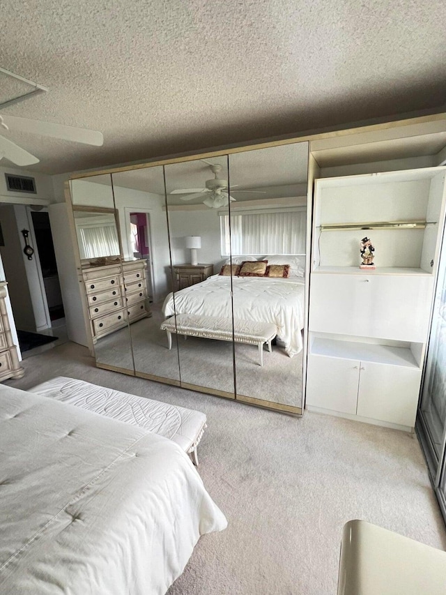 carpeted bedroom featuring ceiling fan, a textured ceiling, and a closet