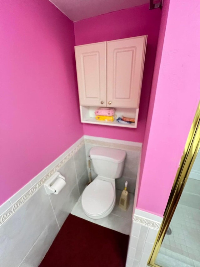 bathroom with tile patterned floors, tile walls, and toilet