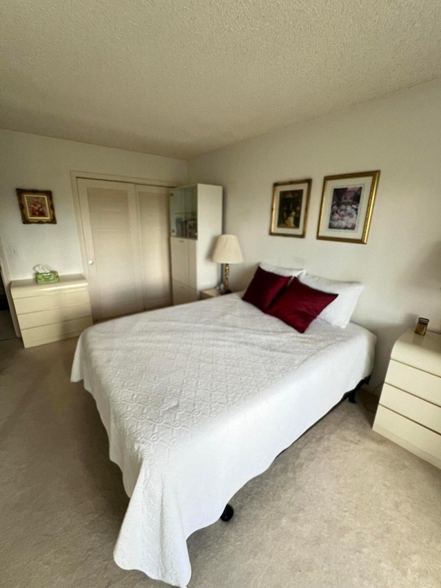 bedroom featuring a textured ceiling, carpet floors, and a closet